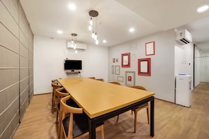 A conference room with a long table, chairs, a flat-screen TV, and wall-mounted air conditioning. - Townhouse 158 Near Netaji Subhash Marg (Gurugram)
