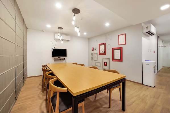 Un salón de conferencias con una larga mesa, sillas, un televisor de pantalla plana y aire acondicionado instalado en la pared.
