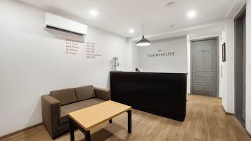 Una recepción con un cartel que dice 'TOWNHOUSE' y una lista de números de habitación en la pared.