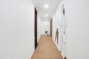 A hallway with a wooden floor, white walls, and a large wall mural. - Townhouse 158 Near Netaji Subhash Marg (Gurugram)