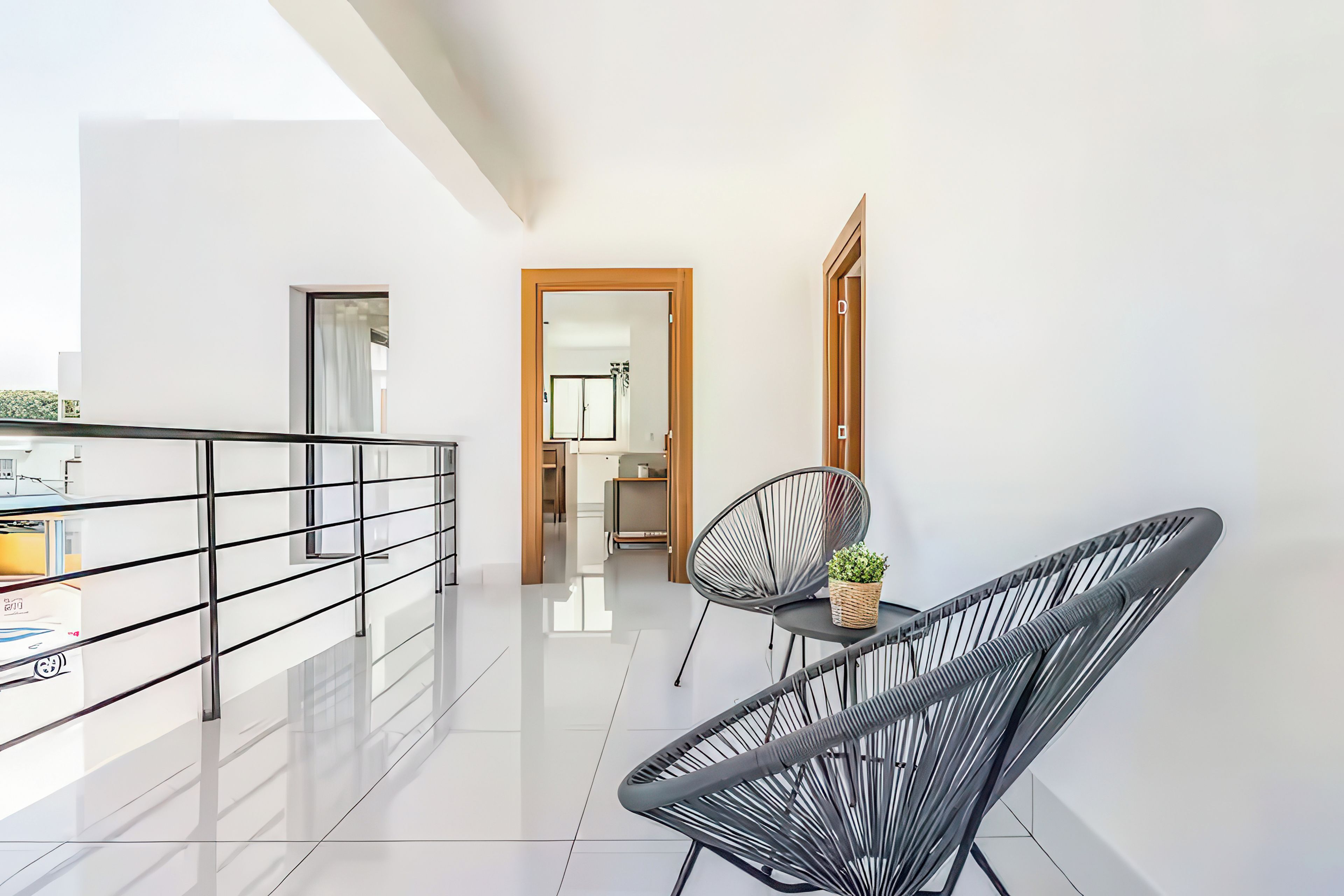 Un apartamento moderno con balcón, un comedor con mesa y sillas, y una cocina visible a través de una puerta abierta.