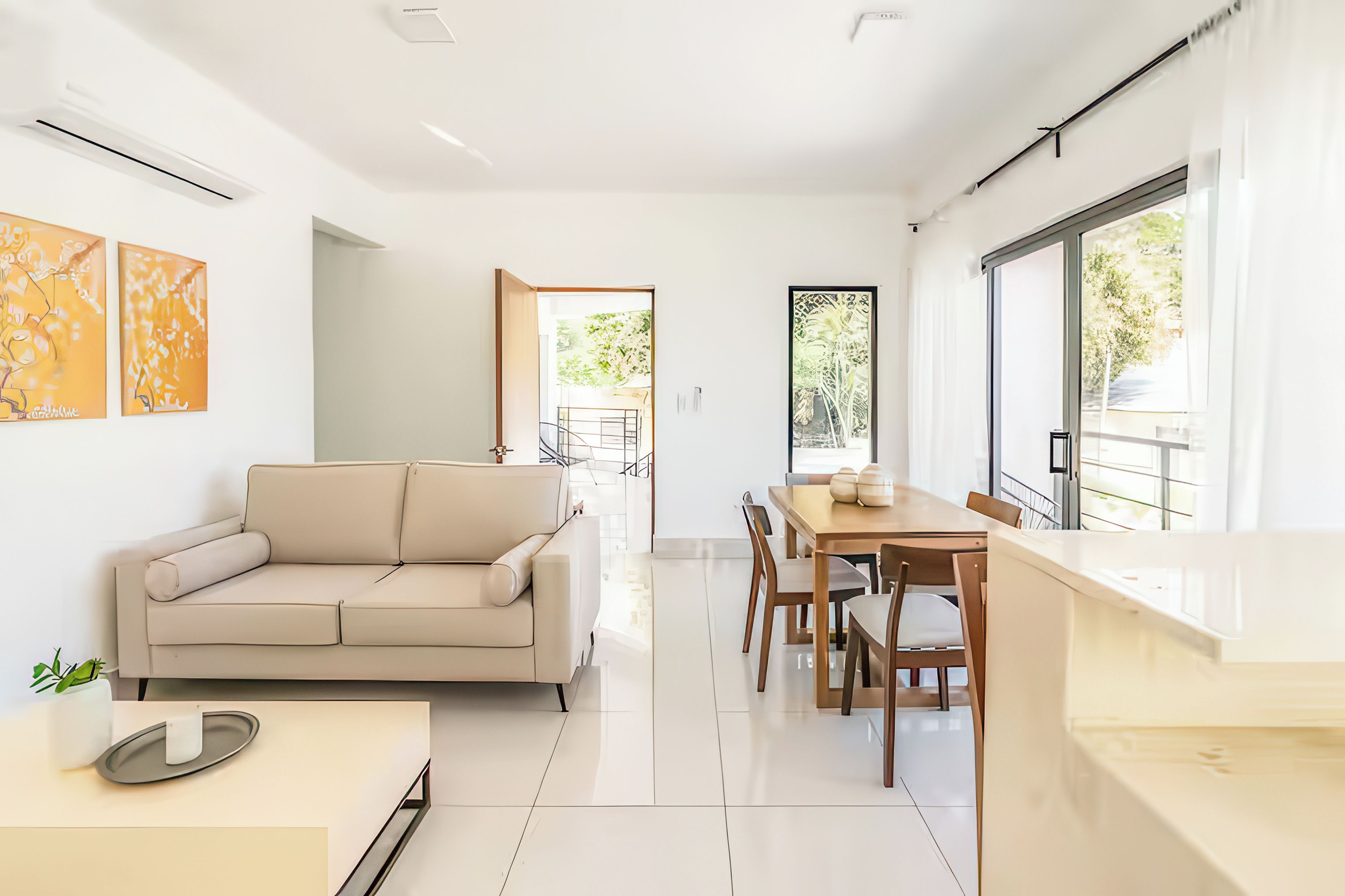 Un intérieur moderne avec un canapé, une table à manger, des chaises et des œuvres d’art accrochées aux murs.