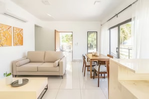 Un interior modern amb un sofà, taula de dinar, cadires i obra d'art a les parets.