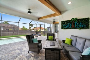 An outdoor patio with a pool, wicker furniture, and a 'Salt Life' sign. - Cape It Easy - 4 Bedroom, Heated Pool, Fenced Yard in Quiet, SW Cape Coral (Cape Coral)