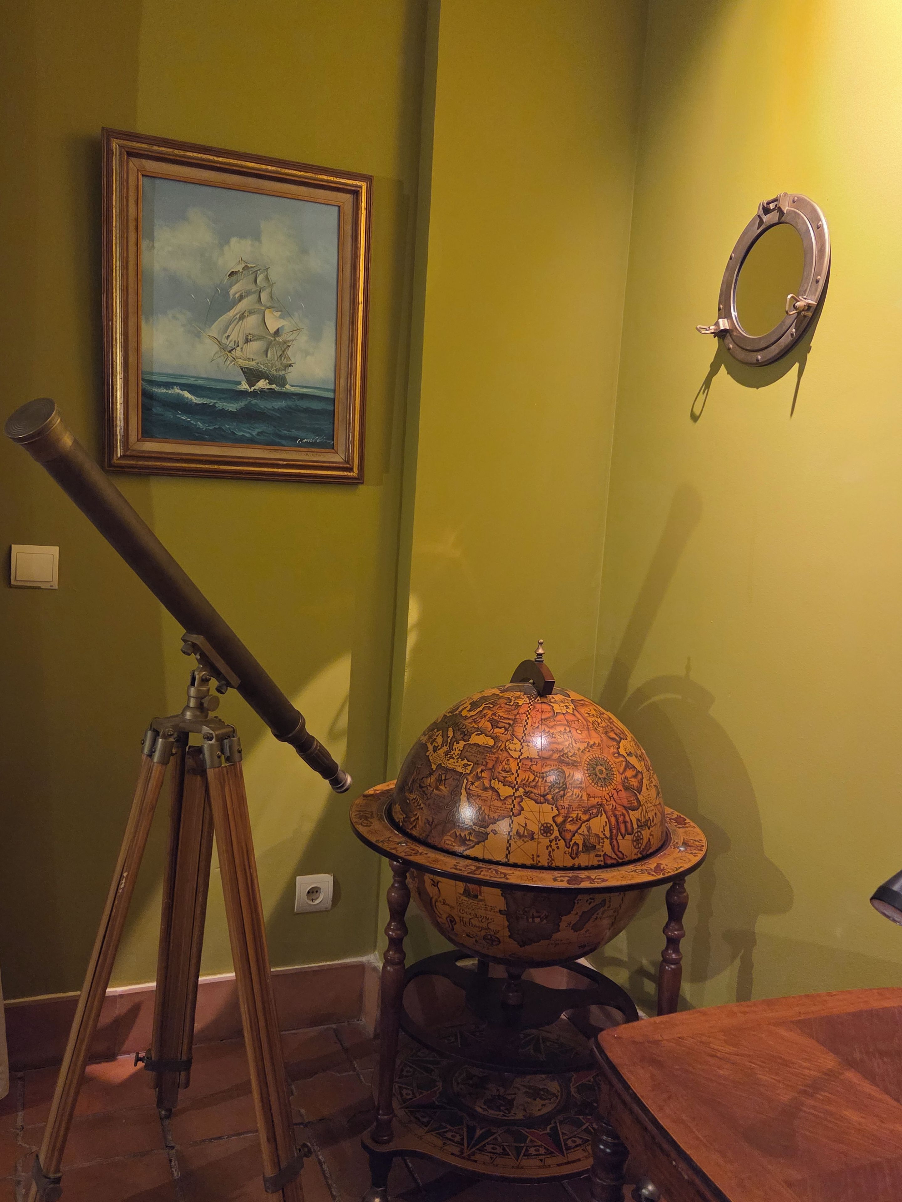 Una habitación con un telescopio, un globo terráqueo y un cuadro en la pared.