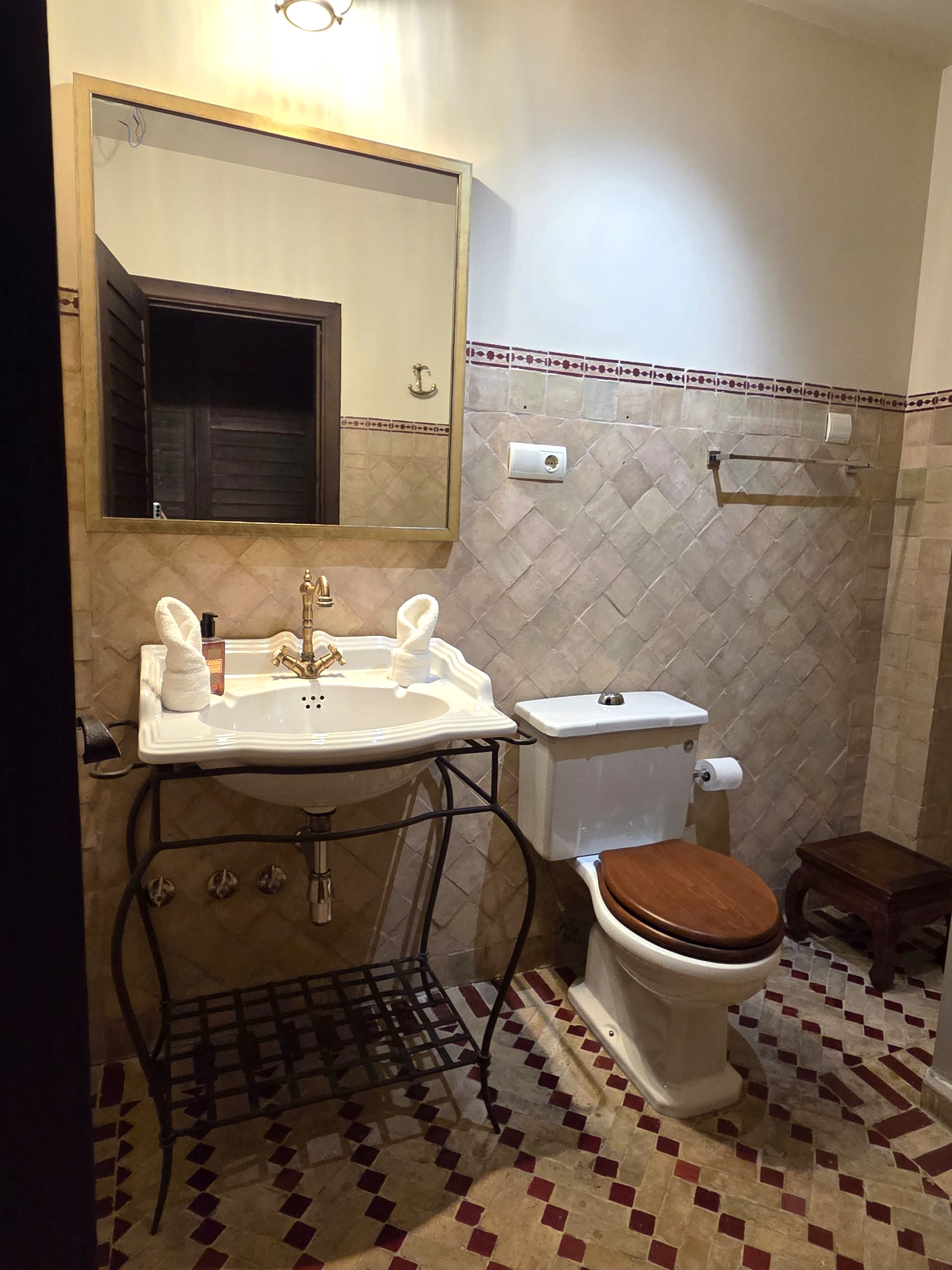 A bathroom with a sink, toilet, and a mirror.