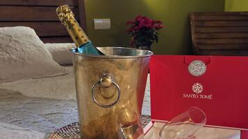 A bed with a metal bucket containing a bottle, a wine glass, and a red box with a logo.