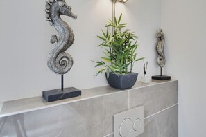 A marble countertop with decorative metal seahorses, a potted bamboo plant, and a modern floor lamp. - Caswell at York Chambers · Luxury 2-Bed Apartment, Sleeps 4, Central Swansea (Swansea)
