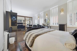 Un dormitorio moderno con una cama grande, un espejo y vistas al salón.