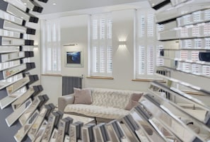 Ein modernes Interieur mit einer Couch, gerahmten Bildern und einem Fenster mit Jalousien.