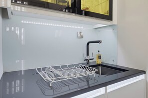 Et køkken med en sort bordplade, en hvid vask og en hane i rustfrit stål.