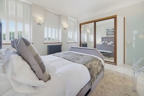 A bedroom with a bed, bedside tables, a mirror, and a view of the outside. - Langland at York Chambers · Luxury 2-Bed Apartment, Sleeps 4, Central Swansea (Swansea)