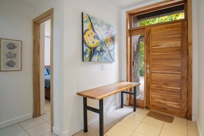 A hallway with a wooden bench, a painting, and a wooden door. - New Listing • Casa Pacifica • 4BR Villa • Private Pool • Pacifico (Playas del Coco)