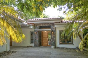 A house with a stone entrance, a wooden door, and a window on the right. - New Listing • Casa Pacifica • 4BR Villa • Private Pool • Pacifico (Playas del Coco)