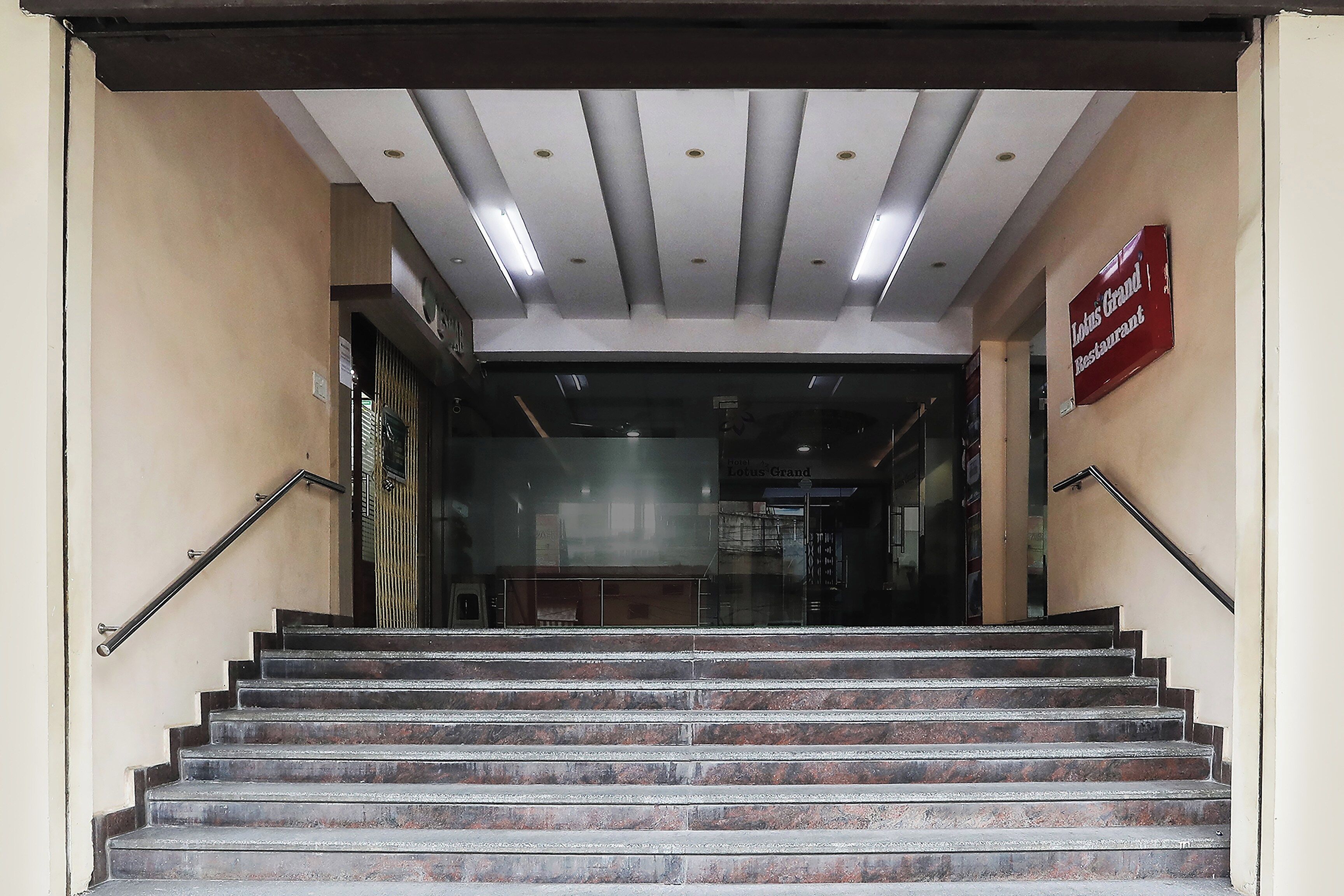 Una escalera conduce a la entrada de un hotel, con un cartel que anuncia 'Lotus Grand Restaurant' en la pared.