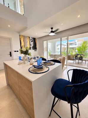 A modern kitchen with a central island, dining chairs, and a view of the outside. - Aqua Esmeralda Beachfront • Luxury Penthouse with Jacuzzi (Dominicus)