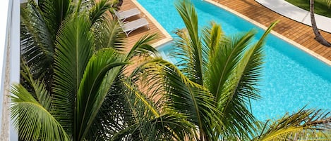 A resort with a swimming pool surrounded by palm trees and modern buildings.