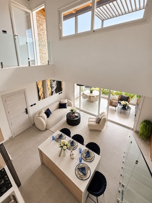 A modern interior with a dining area, seating, and a view to the outside. - Aqua Esmeralda Beachfront • Luxury Penthouse with Jacuzzi (Dominicus)