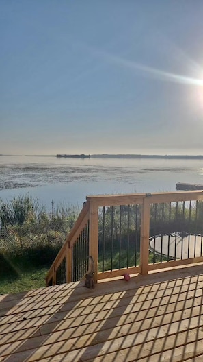 A wooden deck with a metal railing overlooking a calm body of water. - Pet friendly Waterfront Stay Near Wineries, Beaches & Trails with kayaks (Quinte West)