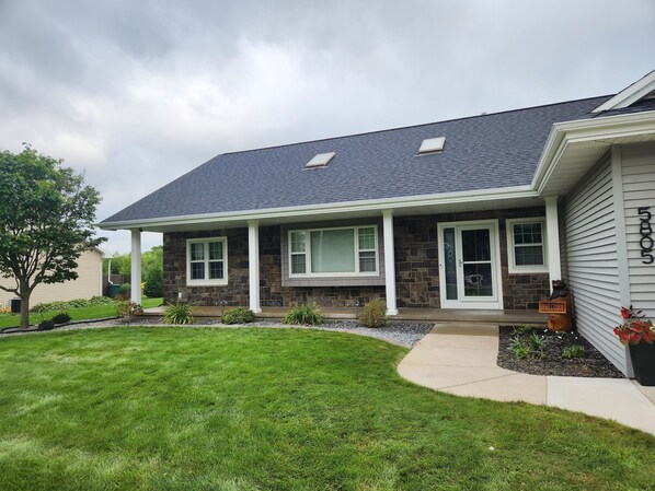 A two-story house with a stone facade, a covered porch, and a well-maintained lawn.