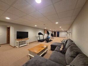 A spacious living room with a television, exercise equipment, and a couch.