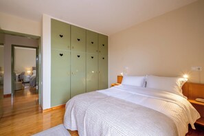 A bedroom with a large bed, a wardrobe with multiple compartments, and a bedside table with a lamp. - Villa Elisa Sounio - Sea and Poseidon Temple View (Sounio)