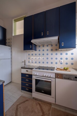 Uma cozinha com armários azuis, fogão branco e painel de azulejos.