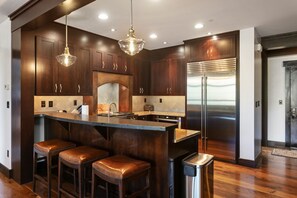 Een moderne keuken met een centraal eiland, roestvrijstalen apparatuur en houten kastjes.