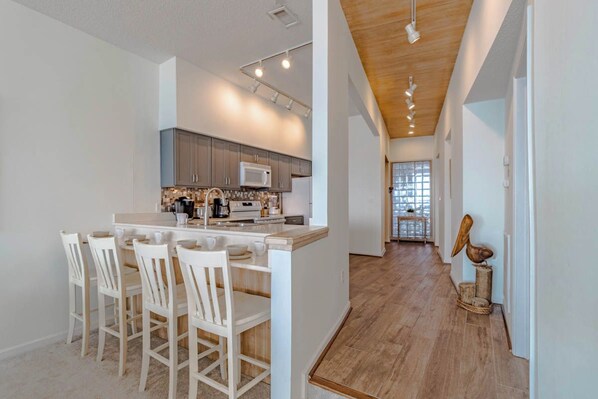 Une cuisine moderne avec des meubles blancs, un îlot central et un coin repas avec des chaises blanches.