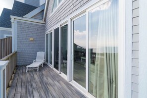 Een overdekt terras met een witte stoel en schuiframen.