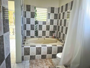 A bathroom with a bathtub, toilet, and a window with blinds. - Charming bed & breakfast with 5 bedrooms in quaint Coral Gardens (coral gardens)