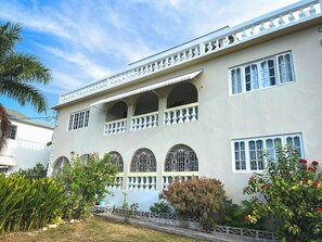 A two-story building with a balcony and arched windows. - Charming bed & breakfast with 5 bedrooms in quaint Coral Gardens (coral gardens)