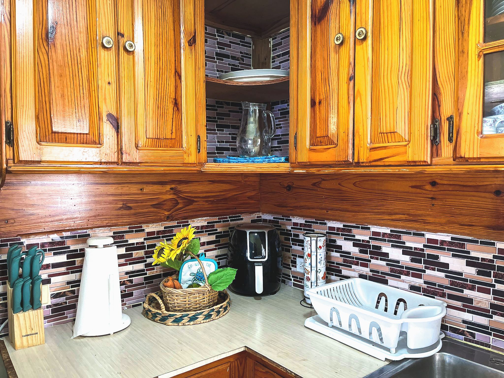 A kitchen with wooden cabinets, a coffee maker, a sink, and a decorative basket with sunflowers.