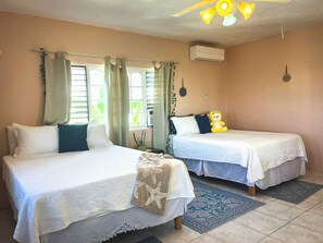 A room with two beds, a ceiling fan, an air conditioning unit, and a decorative wall hanging. - Charming bed & breakfast with 5 bedrooms in quaint Coral Gardens (coral gardens)