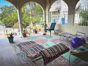 A sunlit patio with a lounge area, potted plants, and a view of the garden. - Charming bed & breakfast with 5 bedrooms in quaint Coral Gardens (coral gardens)