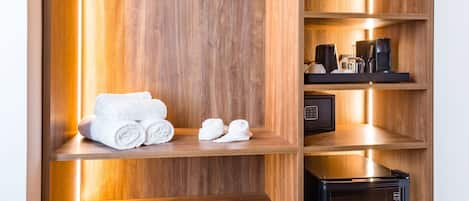 A wooden storage unit with multiple shelves, a hanging rack, and a small black appliance.