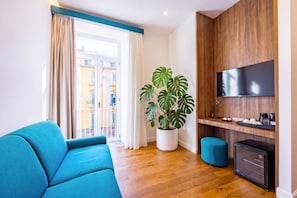 Ein modernes Wohnzimmer mit einer Couch, einem Topfpflanzen, einem Fernseher und einer Kaffeemaschine.