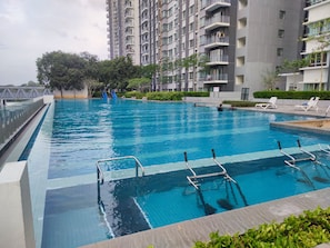 Una piscina amb aigua transparent i blava, envoltada d'un edifici modern amb balcons.