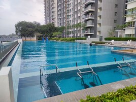 A swimming pool with a clear blue water, surrounded by a modern building with balconies.
