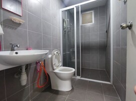 A bathroom with a white sink, toilet, and shower enclosure.