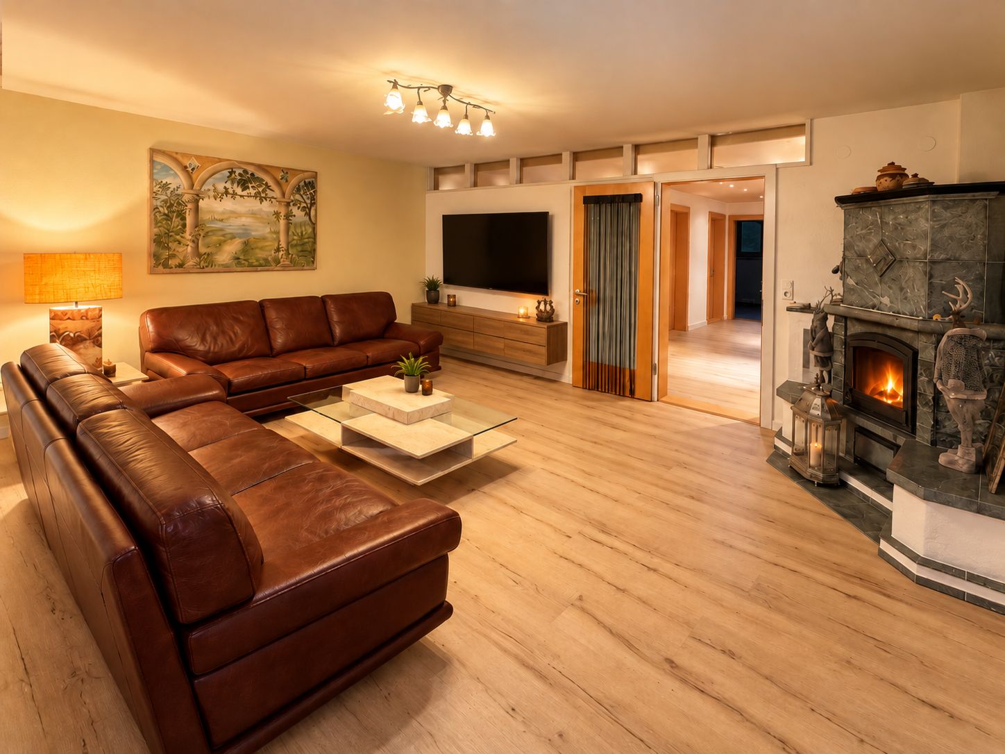 A modern living room with a sectional sofa, a flat-screen TV, a fireplace, and a painting on the wall.