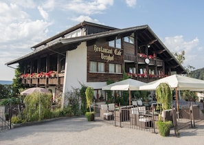 En restaurant med udendørs siddepladser og en træfacade.