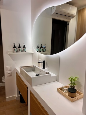 A modern bathroom with a white sink, a mirror, and a shelf with toiletries. - Luxury Villa in Madrid (Madrid)