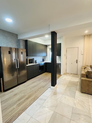 A modern kitchen with stainless steel appliances, a microwave, and a built-in oven. There is a wooden floor and a beige rug. - Luxury Villa in Madrid (Madrid)