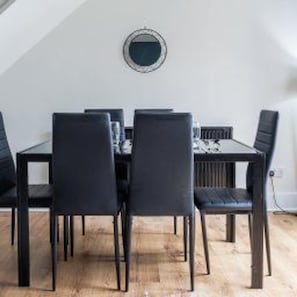 A dining table with six chairs, a round wall clock, and a radiator. - Central Sunderland - Sleeps 7 - House - Parking (Sunderland)