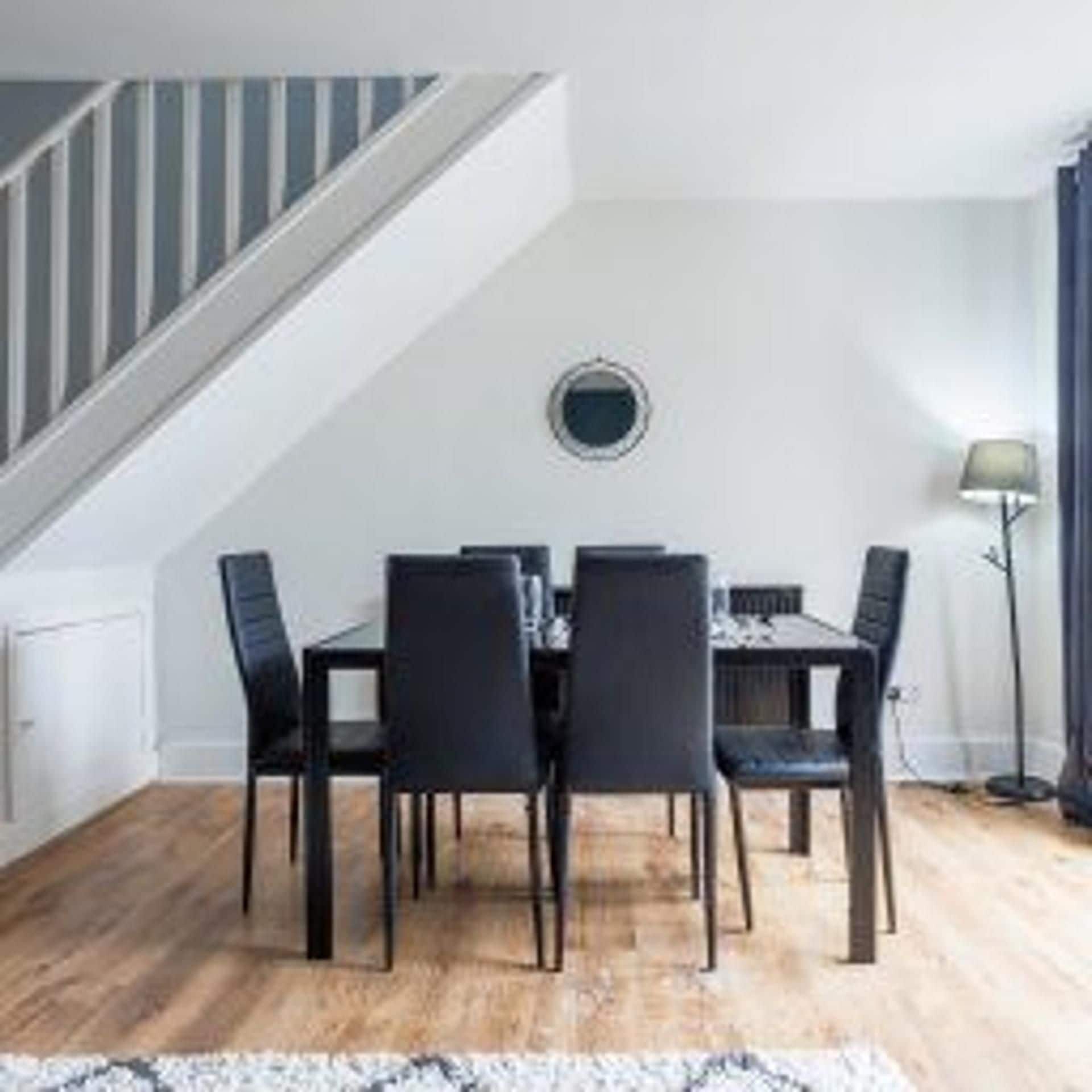 A dining area with a table and chairs, a staircase, and a lamp.
