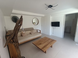A modern living room with a sofa, coffee table, and a television. - Vacation rental with a private pool in a beautiful tropical garden near Raisins Clairs Beach (Saint-François)