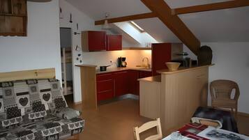 Un espace de vie compact comprenant une kitchenette, un coin repas et un canapé.