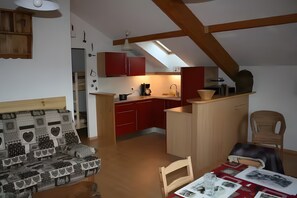 Un espai vital reduït amb petita cuina, zona de menjador i sofà.