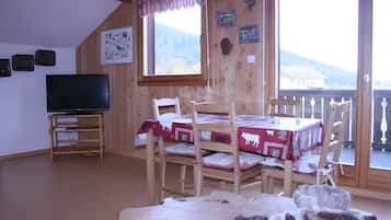 Ein Zimmer mit einem hölzernen Etagenbett, einem Fernseher und einem Tisch mit roter Tischdecke.
